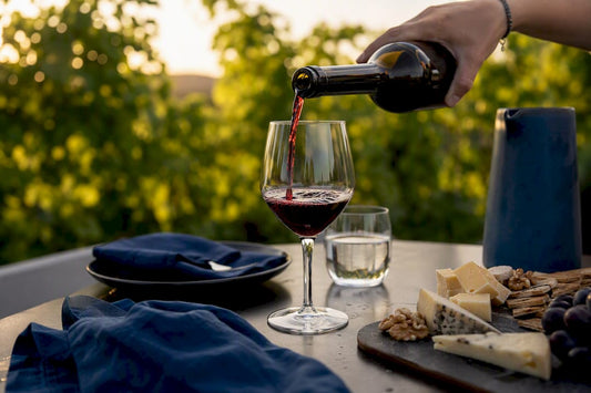 Hand pouring chilled red wine on summer patio